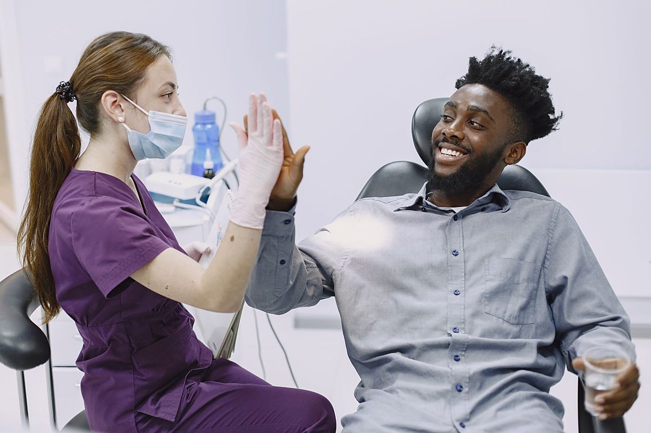 Zufriedener Patient gibt der Zahnärztin nach der Behandlung ein High-Five